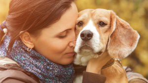 Pensive woman cuddling older beagle dog
