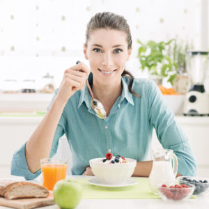 Smiling woman having a relaxing healthy breakfast at home