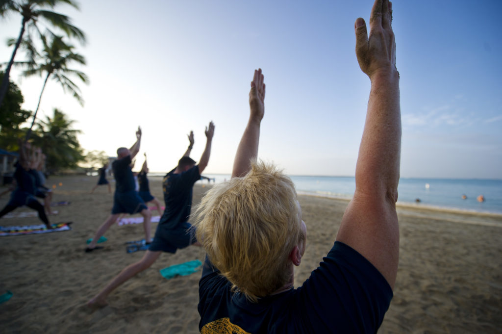 People practising yoga on a beach