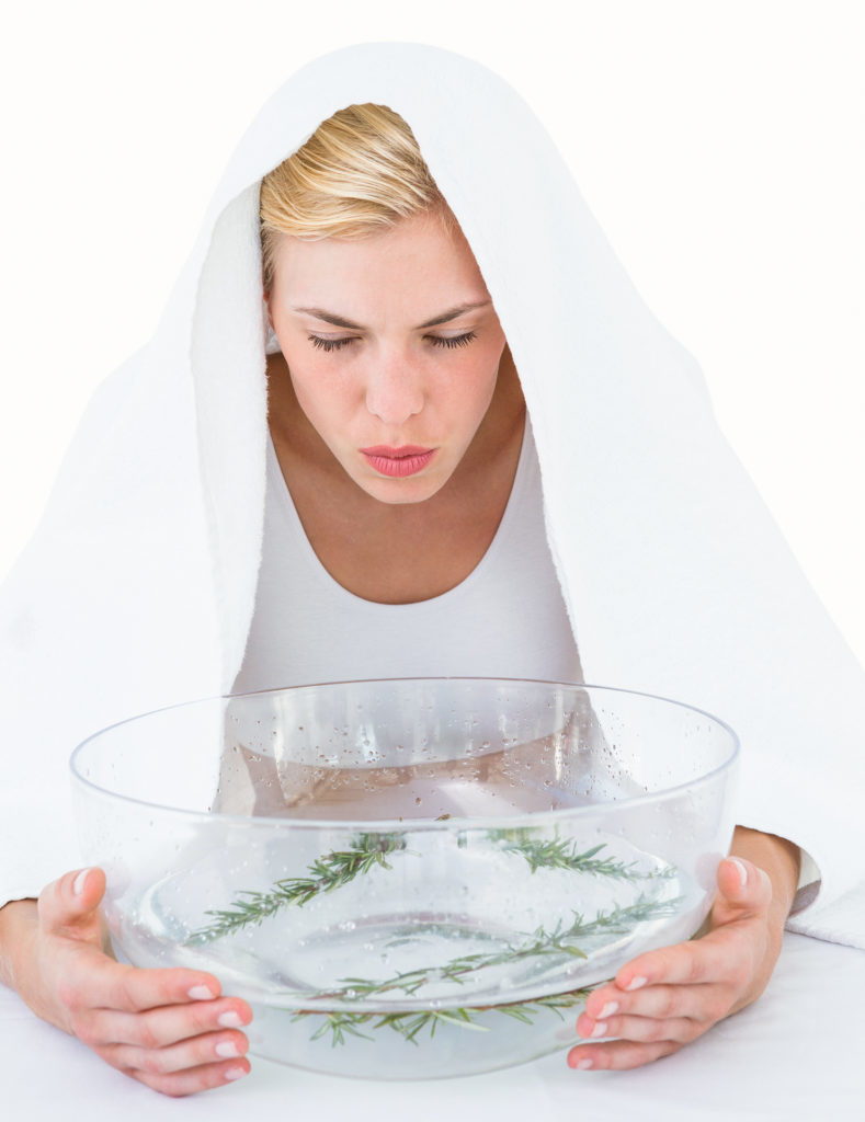 Blonde woman inhaling herbal medicine on white background