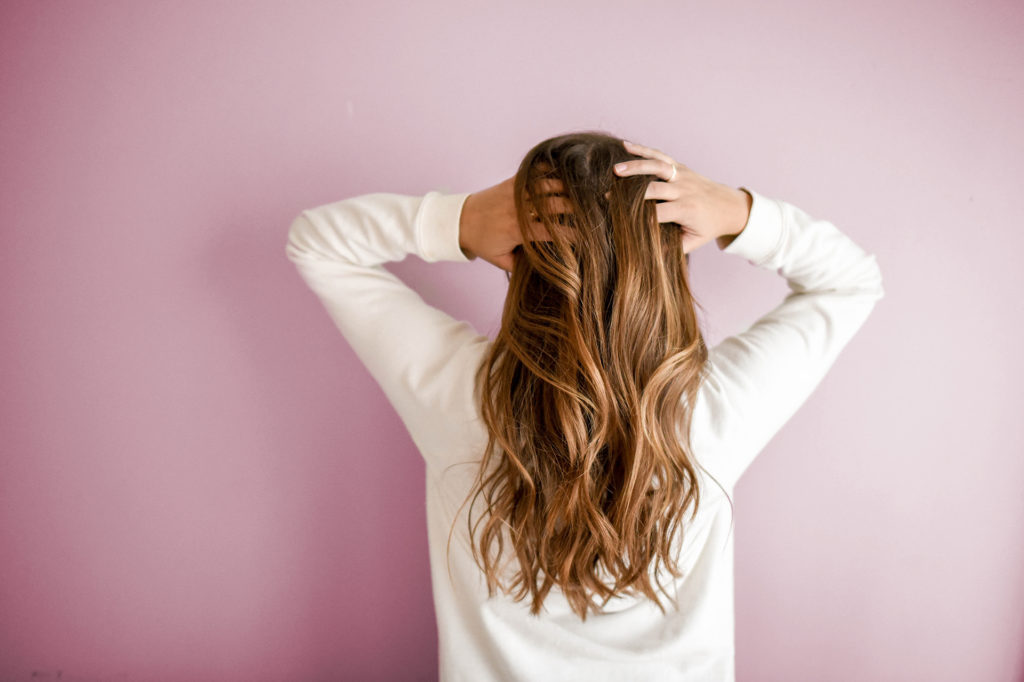 Woman running hands through hair with her back to camera