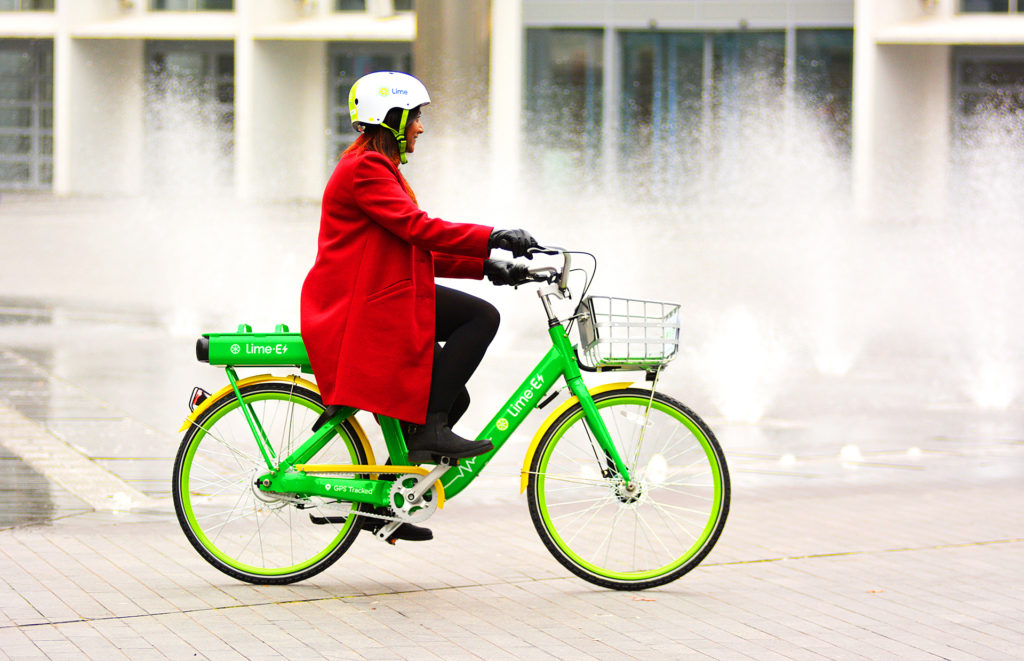 Woman in red coat on lime green bike