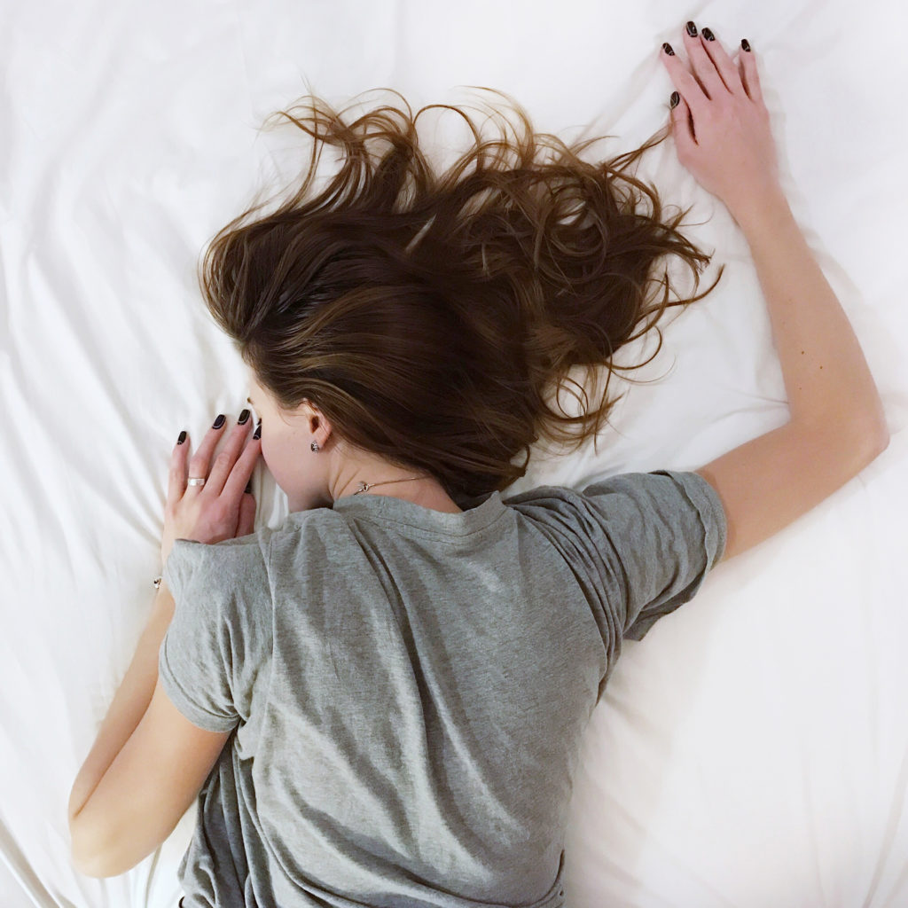 Woman in grey t shirt sleeping face down on mattress
