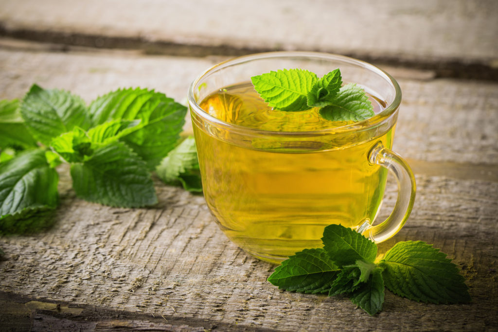 Peppermint tea in a glass cup with leaves