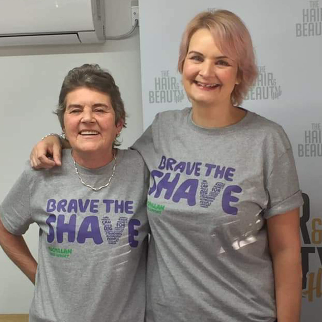 Mother and adult daughter in grey Macmillan t shirts at hairdressers, smiling