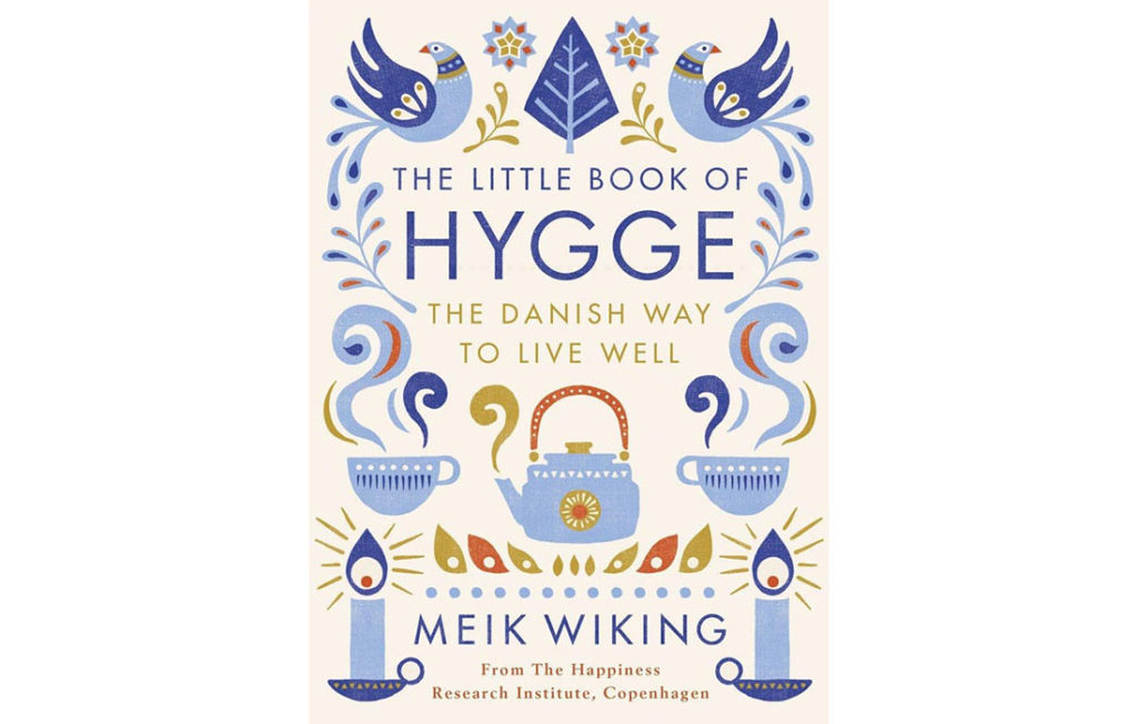 Cover of The Little Book Of Hygge, symmetrical patterns of blue birds, candles and steaming teacups