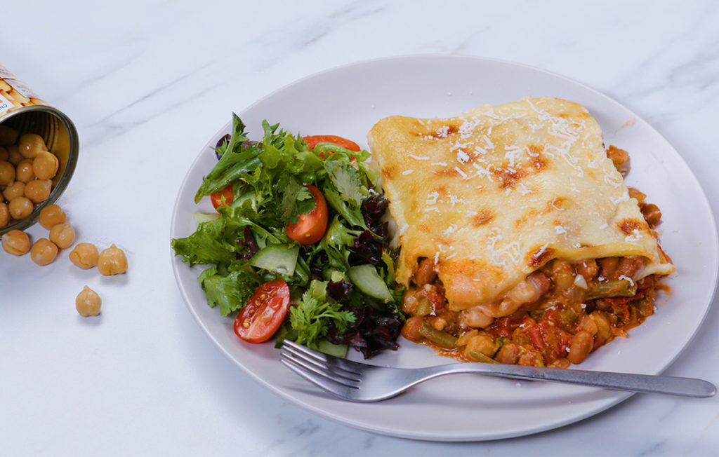 Vegetable lasagne with golden cheesy topping on a plate with salad.