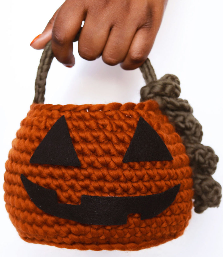 Person holding pumpkin basket by handle