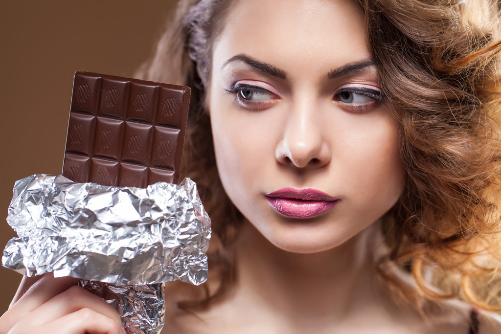 Woman looking sideways at large bar of chocolate
