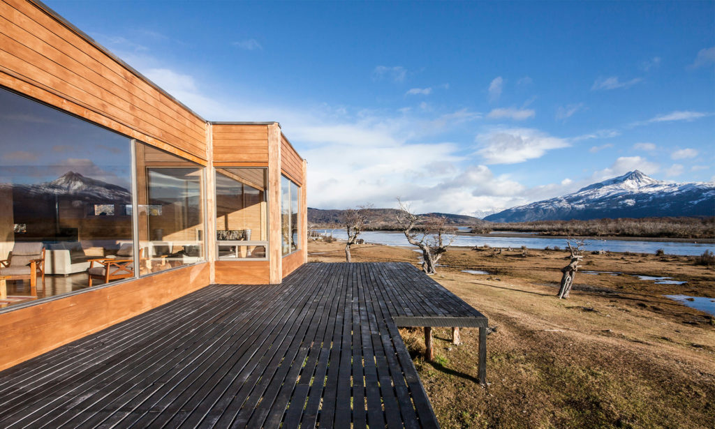 Hotel with open wooden terrace on stilts, overlooking river and hills beyond