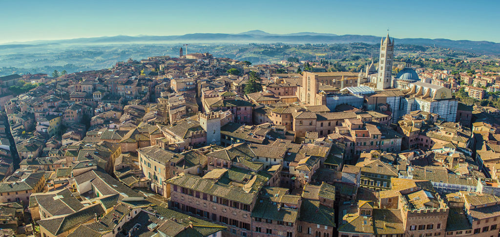 Panoramic bird eye view of Siena, Italy, taken from Torre del Mangia (highest tower in Siena). The dominant building on the right is Siena Cathderal.; Shutterstock