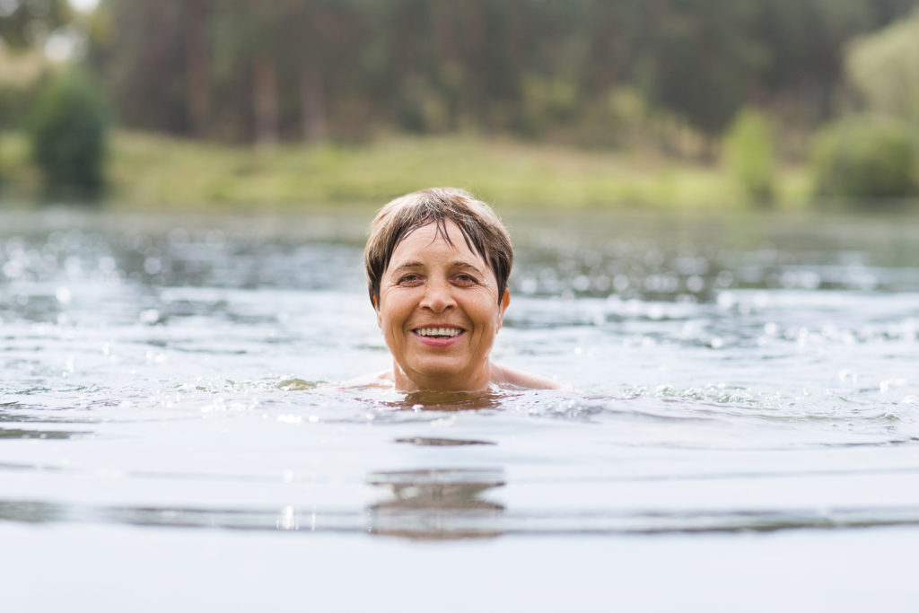 Healthy senior woman swimming in the lake, enjoying keeping fit after retirement