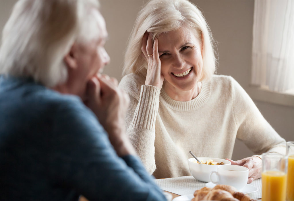 Mature couple smiling at each other over breakfast table