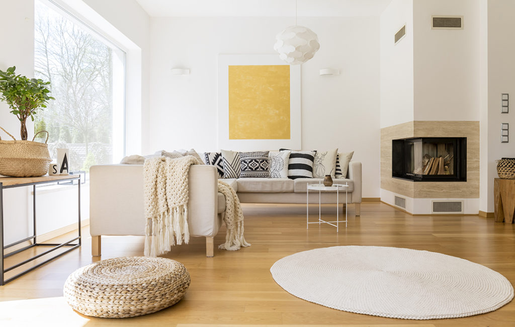 Calming room with neutral colours, laminate floor, round white rug and sleek modern stove