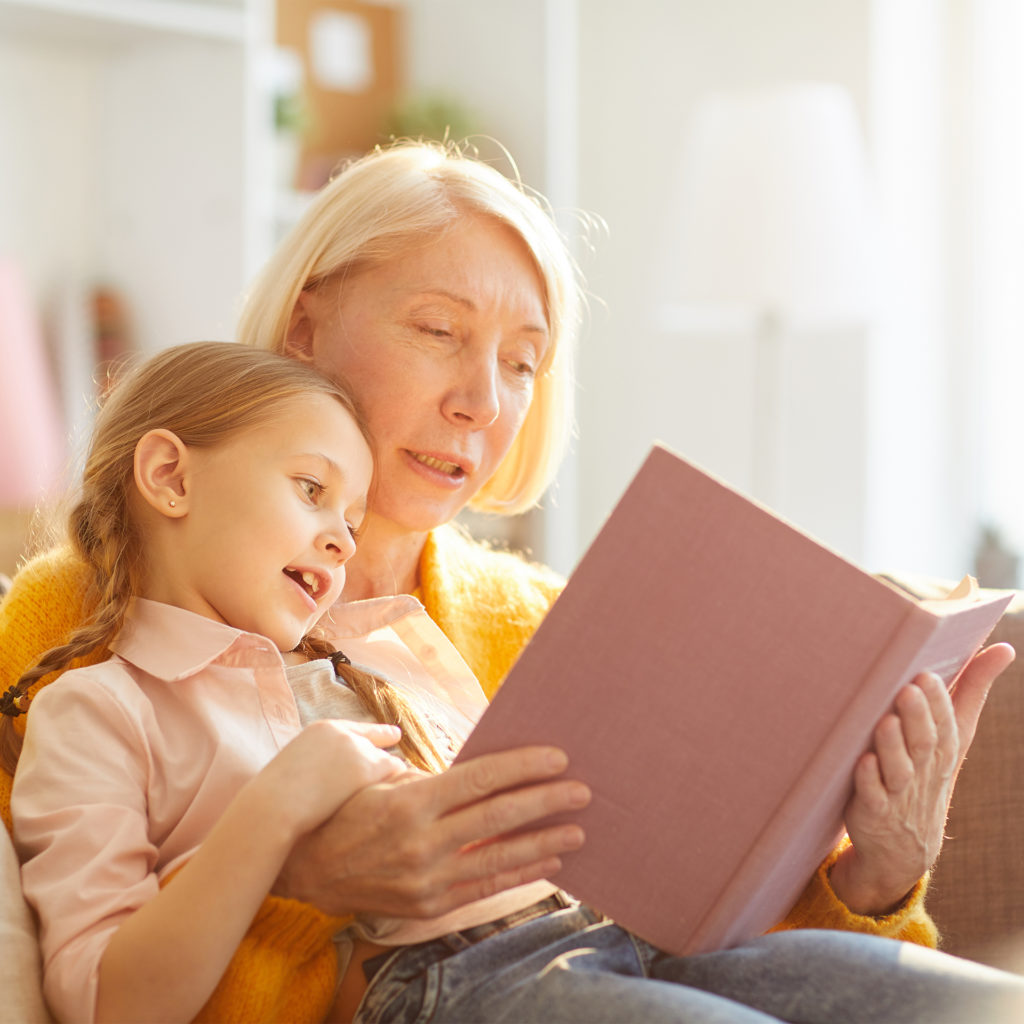 Mature woman reading book with happy girl age 7. Setting boundaries