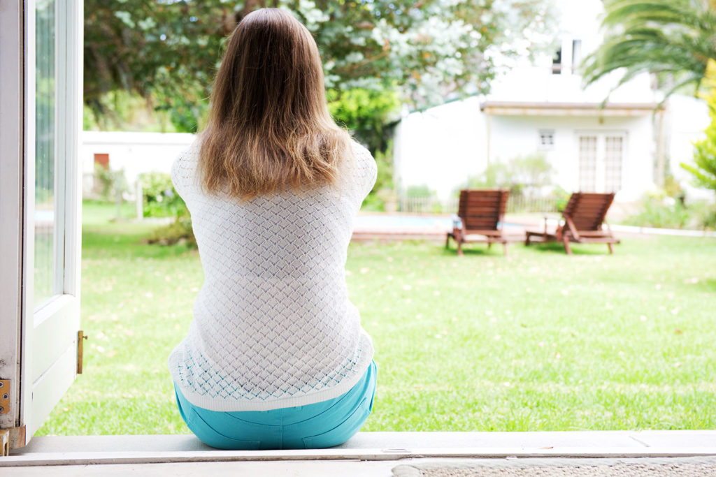 Back of woman sitting and looking outside of home