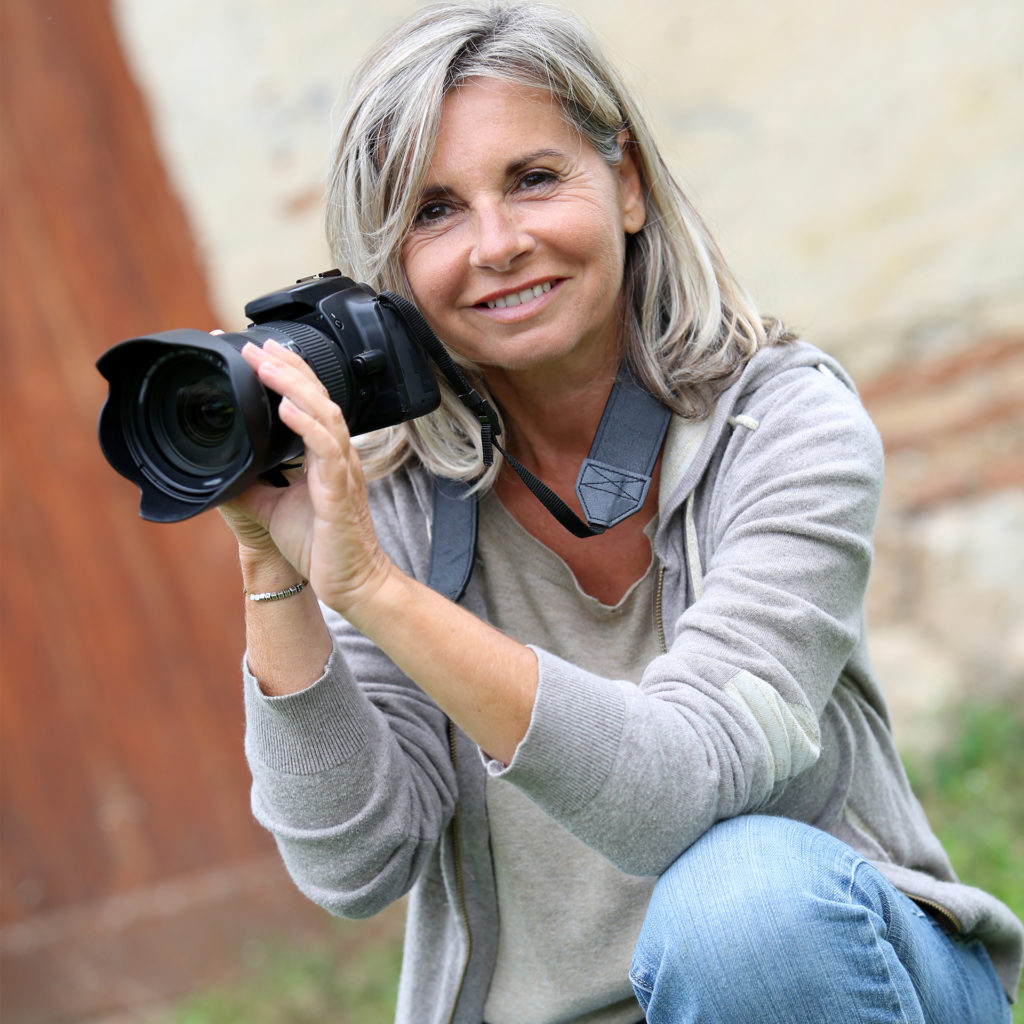 Mature woman kneeling, aiming professional camera