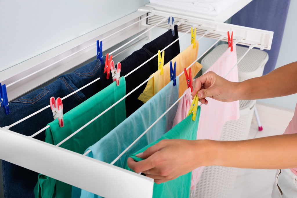 Close-up Of Woman Hanging Wet Clean Cloth On Clothes Line In laundry Room;