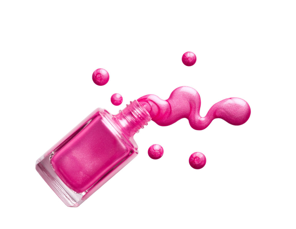Bright pink nail varnish spilling out of the bottle onto white background