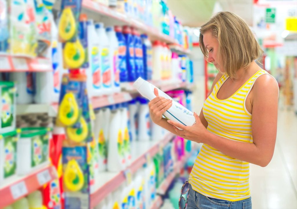 Woman choosing laundry detergent in grocery store.