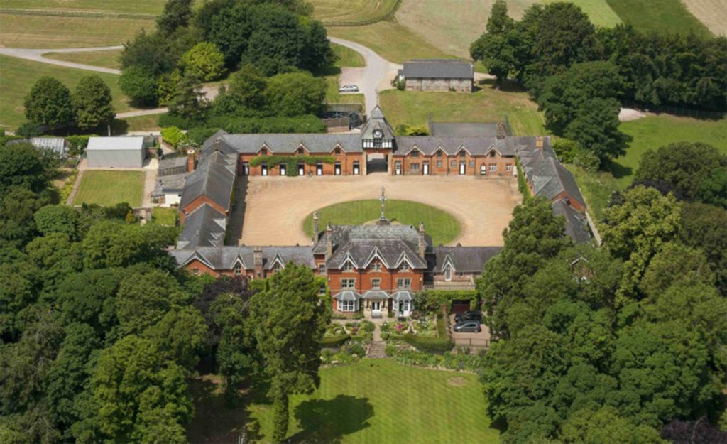 Aerial view of grand house with large courtyard and wooded grounds