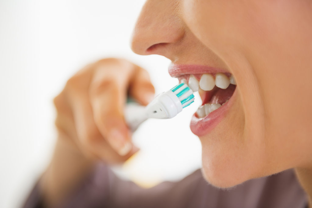 Closeup on happy young woman brushing teeth; 