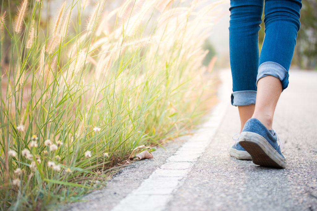 Pair of women's feet in trainers walking along edge of road