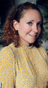 Niki Webster of Rebel Recipes, smiling young woman with curly brown hair wearing spotted yellow blouse