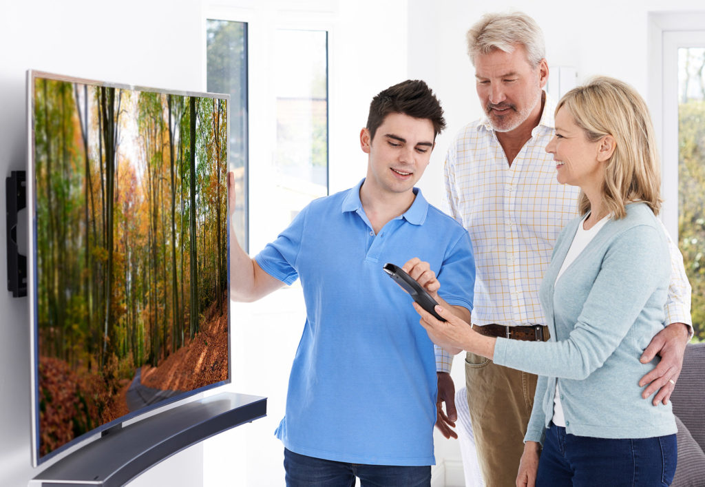 Man Demonstrating New Television To Mature Couple At Home
