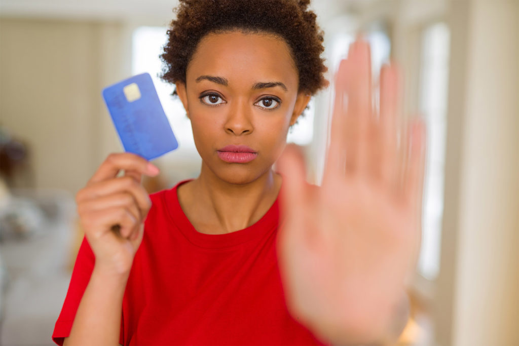 Woman holding credit card, other hand up in a Stop gesture