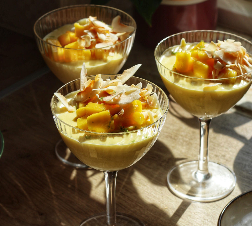 3 large wineglasses filled with white chocolate mousse, topped with mango and toasted coconut