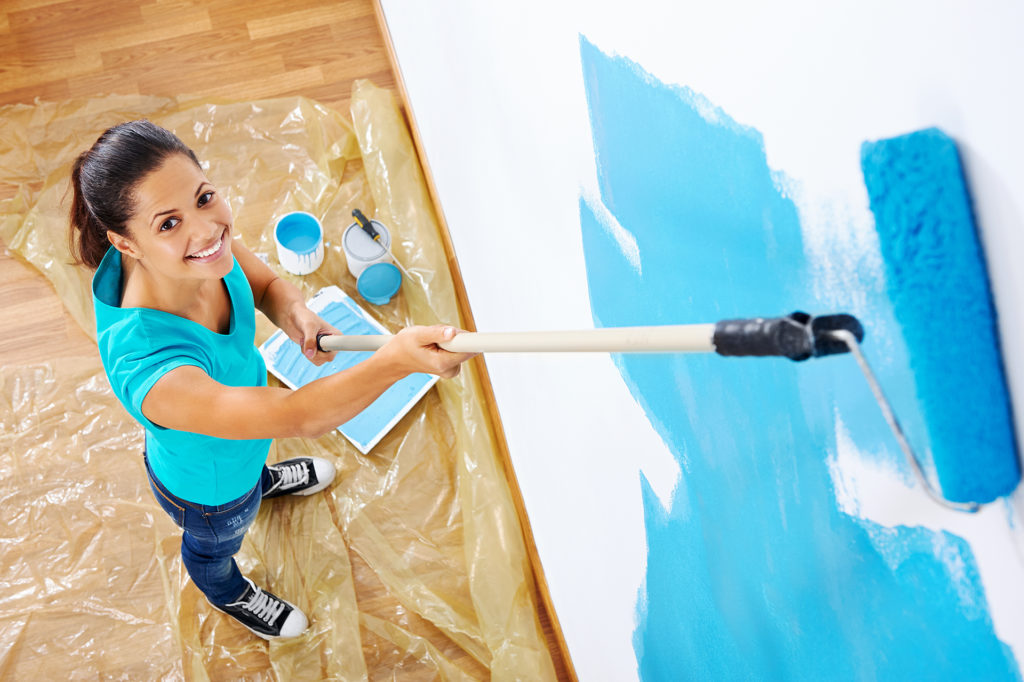 overhead view of woman painting new apartment standing on wooden floor; 