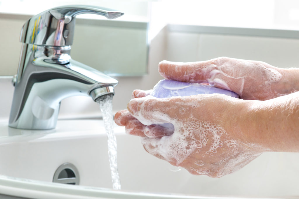 Pair of hands washing with bar of purple soap