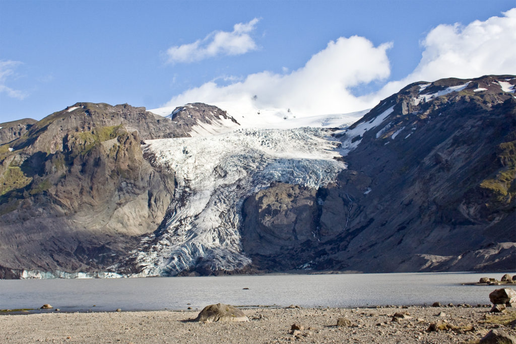 Barren landscape, range of mountains with extensive glacier reaching down to lake