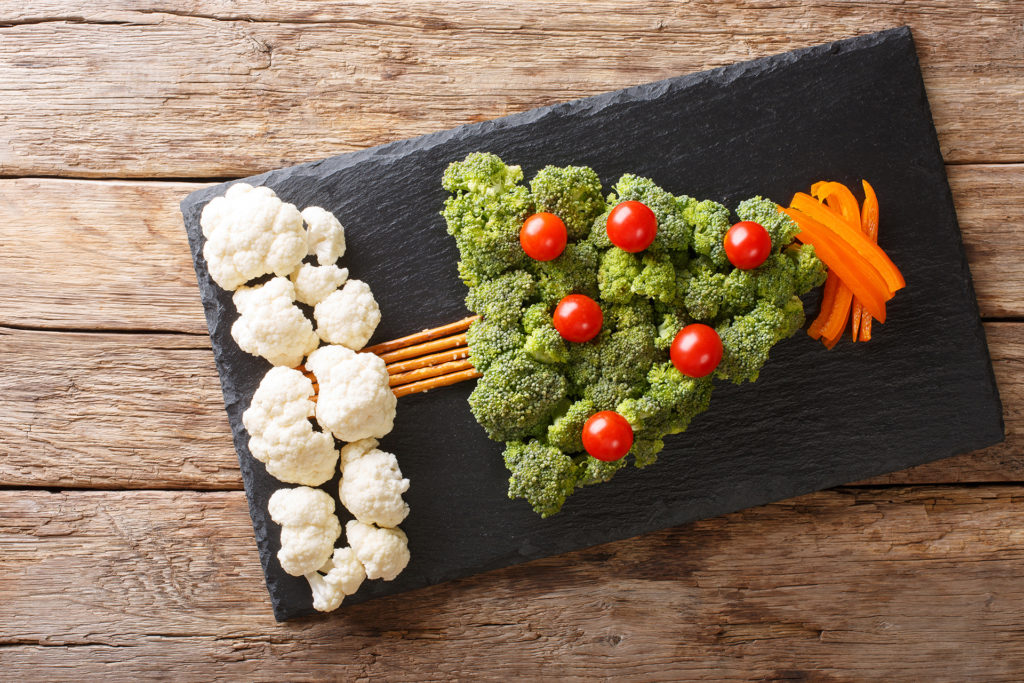 Beautiful food: Christmas tree of broccoli, cauliflower, tomatoes, pepper closeup on a table. Horizontal top view from above ; 