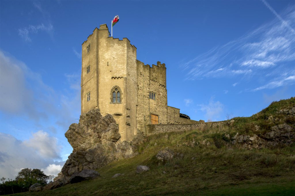 Medieval looking castle on rocky outcrop, blue sky, flag flying