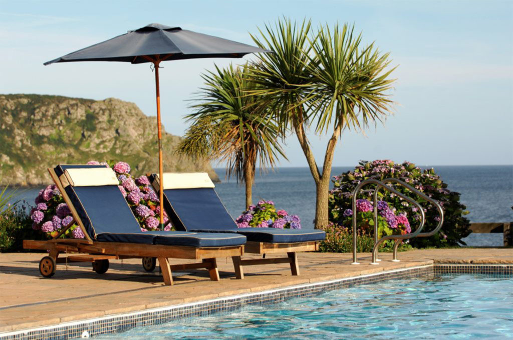 Sun loungers, palm trees, pool and sea beyond