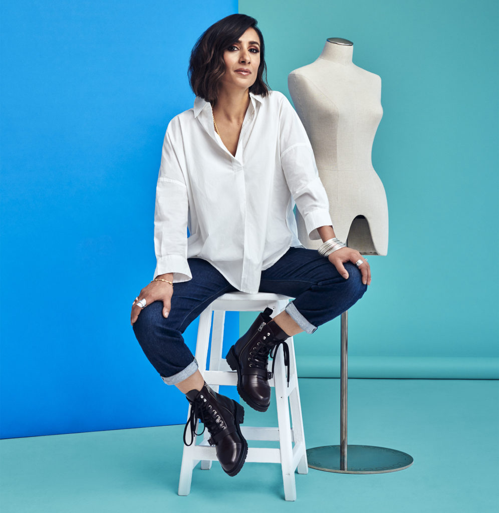 Young Asian woman in white shirt, dark skinny jeans and lace-up ankle boots, blue and turquoise background