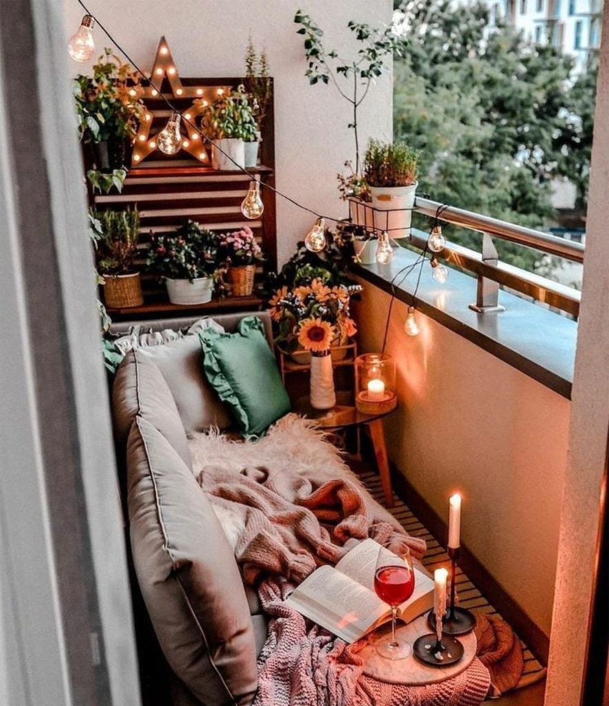 Cosy balcony with plants, bench with throw and candles