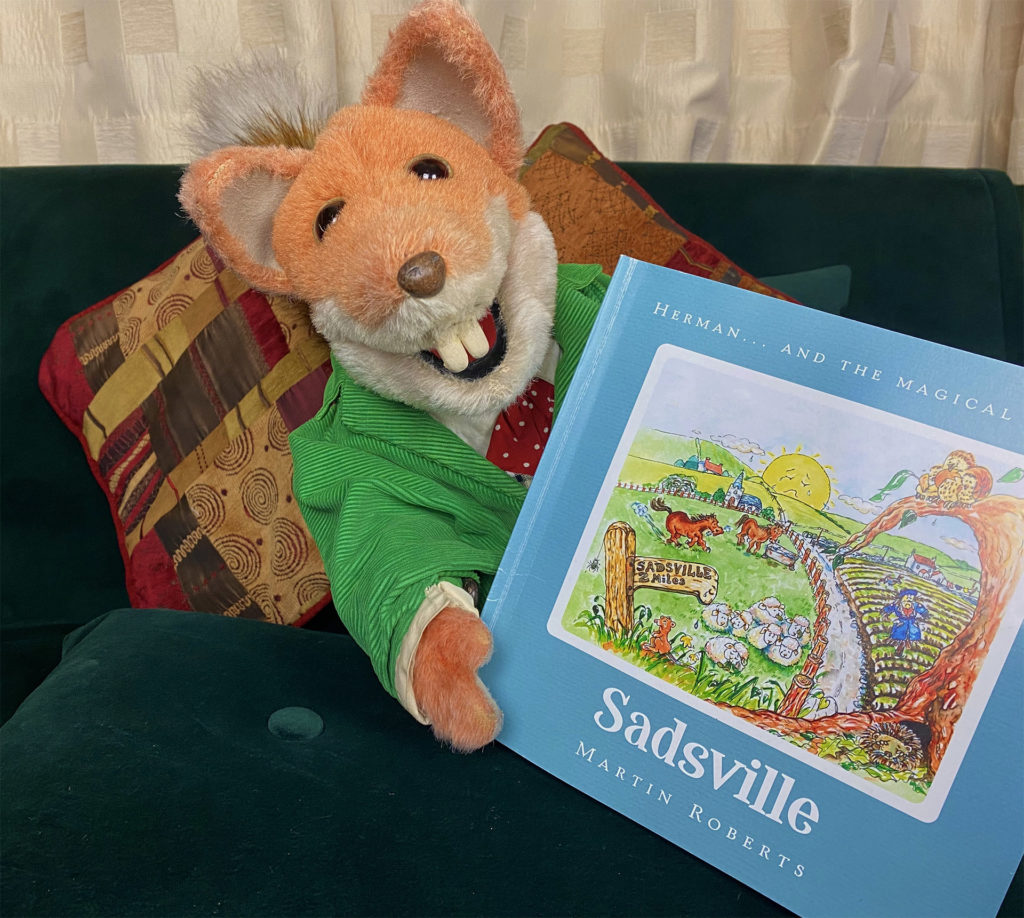 Puppet character Basil Brush holding children's book Sadsville