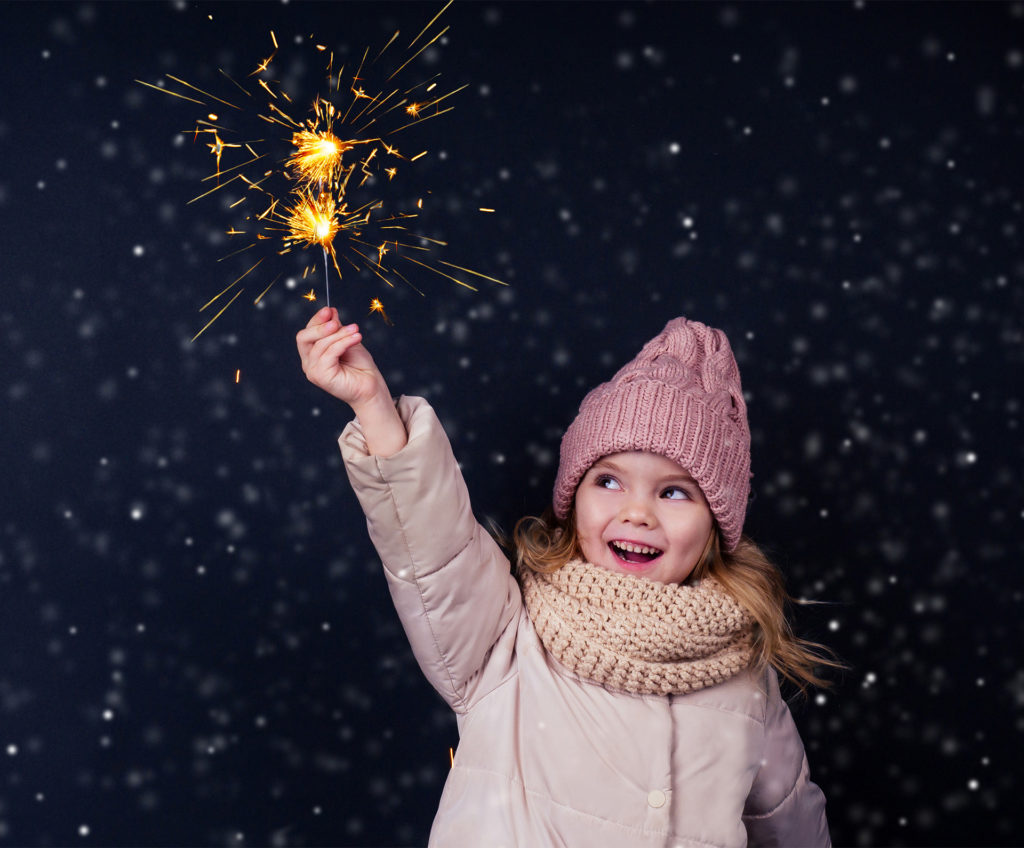 Dogs and fireworks: little girl in a knitted pink hat holding sparkler