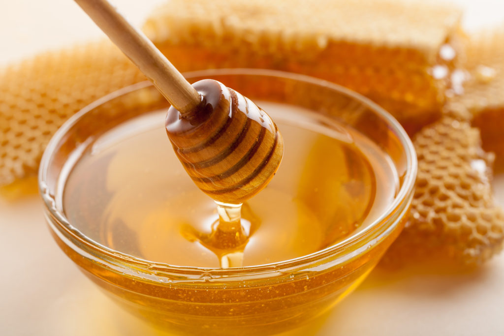 Honey in a bowl and coating a stick