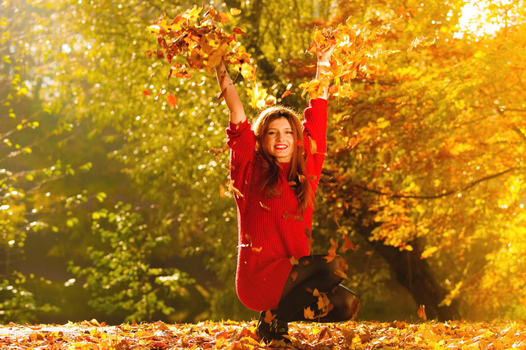 Happiness carefree. woman relaxing in autumn park throwing leaves up in the air with arms raised up. Beautiful girl in colourful forest foliage outdoor.; 