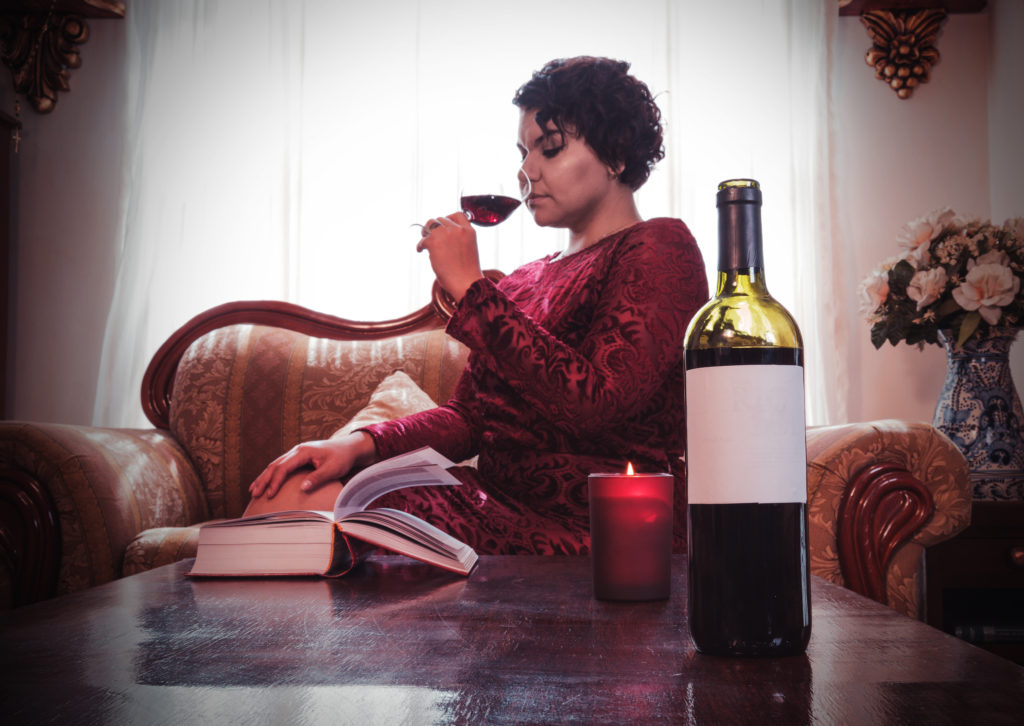 Woman having a glass of red wine,white label wine bottle; 
