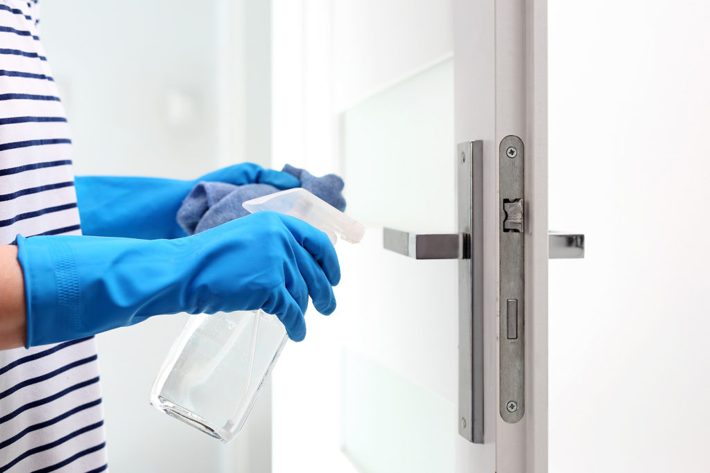 Cleaning the house, cleaning door handles. Prevention and prevention of infection. The woman cleans the apartment.; 