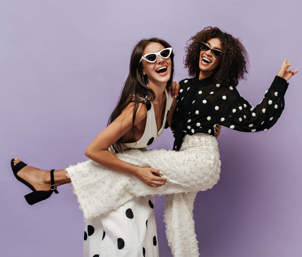 2 young women in polka dot clothes pose laughing