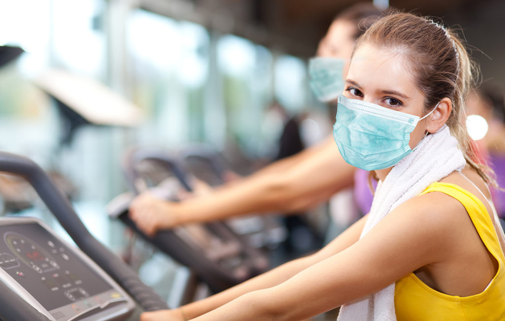 Group of people doing fitness in a gym wearing a mask, coronavirus concept; 