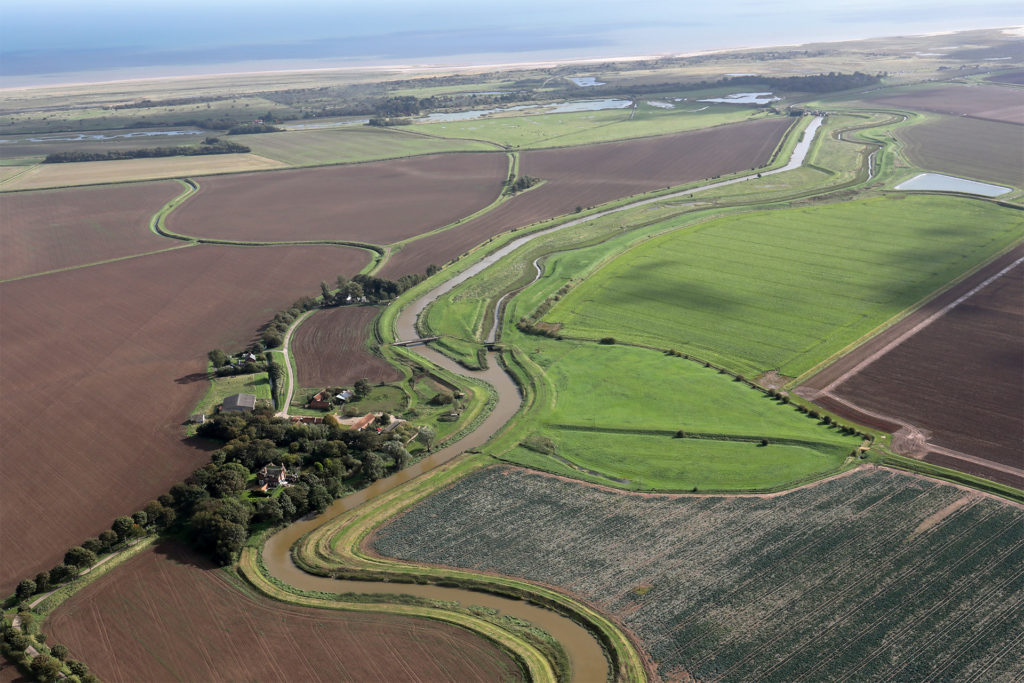 Aerial view of river through flat landscape to the sea, Lincolnshire fens, which inspire crime author Joy Ellis