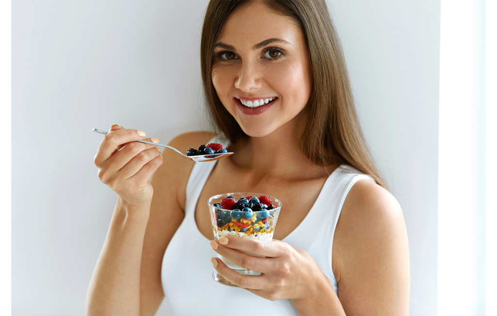 Young woman eating granola and berries breakfast