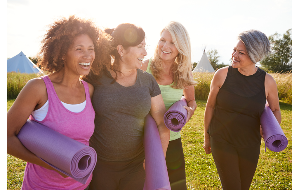Four women outdoors in park with yoga mats